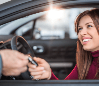 Mulher feliz dentro do seu carro com a chave na mão