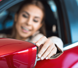 Mulher no carro a mexer no espelho do carro