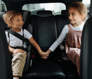 Duas crianças de mão dada no banco de trás do carro