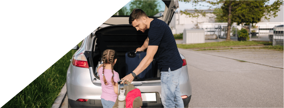 Pai com a filha a pôr malas de viagem no carro