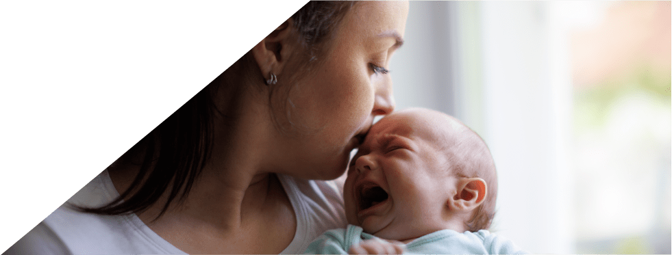 mãe a dar beijinho na testa de bebé a chorar