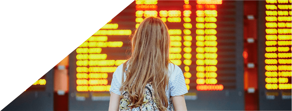 Mulher com mala de viagem na mão a ver um horário de transportes