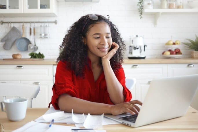 Jovem mulher a usar o computador para consultar ajuda para pagar a renda de casa.