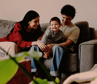 Família sorridente sentada num sofá na sala de estar.