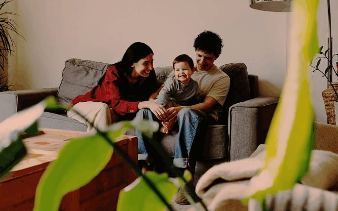 Família sorridente sentada num sofá na sala de estar.