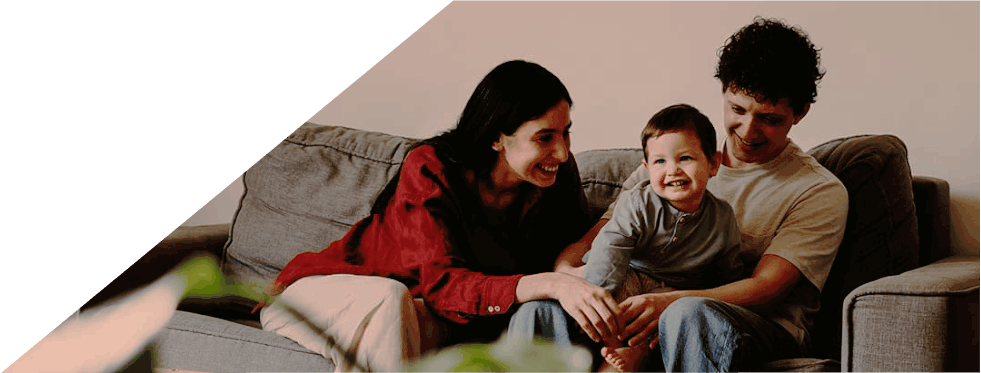 Família sorridente sentada num sofá na sala de estar.