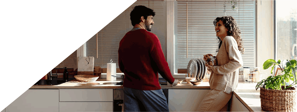 Casal a conversar alegremente numa cozinha moderna.