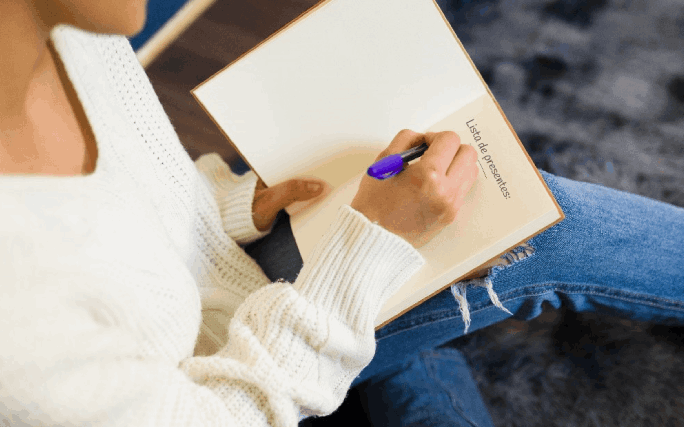 Mulher escreve a lista de presentes, depois de aprender como poupar nas prendas de Natal.