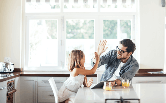 Homem numa cozinha com a filha pequena, a pesquisar os principais tipos de seguro.