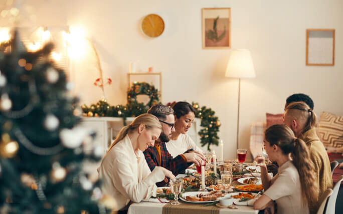 Família reunida à volta de uma mesa de Consoada repleta de receitas de natal saudáveis. 