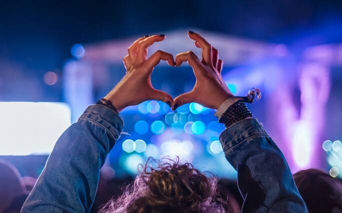 Fã faz um coração com as mãos num concerto dos festivais de verão. 