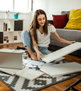 Mulher jovem faz as suas próprias reparações em casa, montando umas prateleiras.