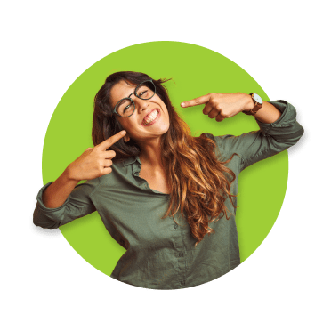 Rapariga de óculos, cabelo comprido e camisa verde, sorridente, a apontar para os próprios dentes