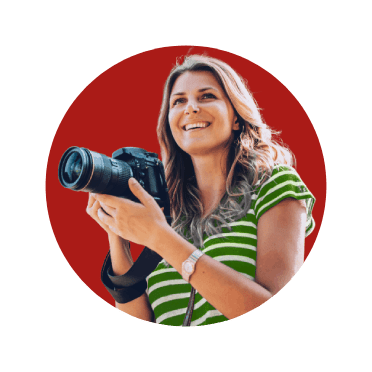 Rapariga sorridente, de máquina fotográfica na mão, em viagem.