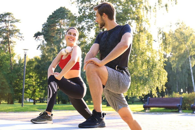 Um casal faz exercícios de aquecimento antes da sua prática de corrida.