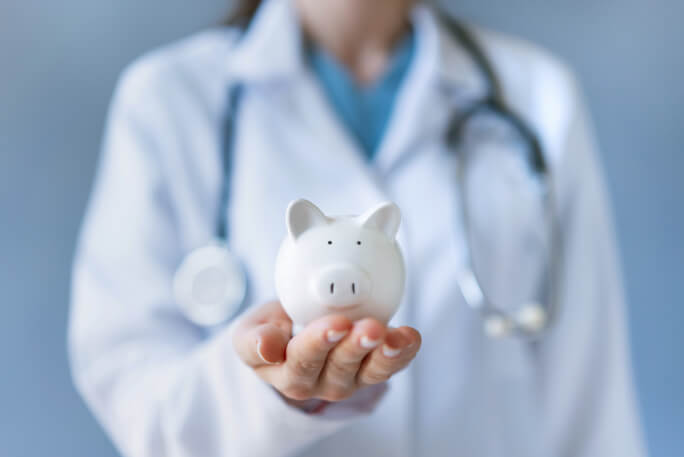 Uma profissional de saúde segura na mão um porquinho-mealheiro