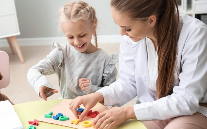 Uma terapeuta trabalha as letras e palavras com uma menina com dislexia.