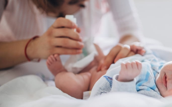 Mãos de uma mãe limpam o umbigo do recém-nascido.