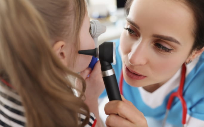 Criança com dor de ouvido a ser examinada por um médico.