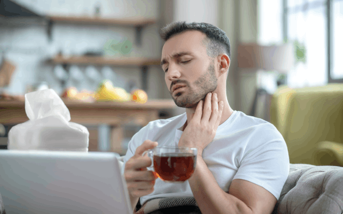 Rapaz jovem a beber chá, para aliviar dor de garganta.