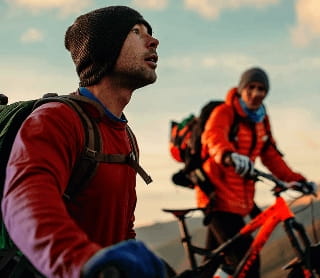 Grupo de ciclistas de montanha a observar a paisagem ao pôr do sol.