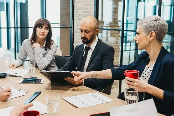 Um homem e duas mulheres em reunião de negócios