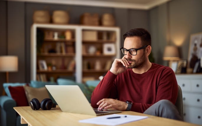 Homem jovem pensativo, a escrever a carta de demissão no seu computador pessoal.