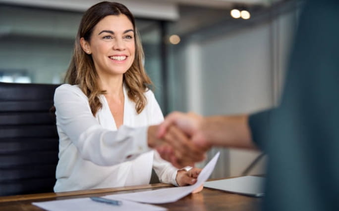 Mulher feliz, aperta a mão ao assinar novo contrato de trabalho.