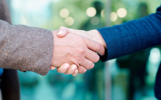 Aperto de mãos num cumprimento entre uma mão masculina e outra feminina.